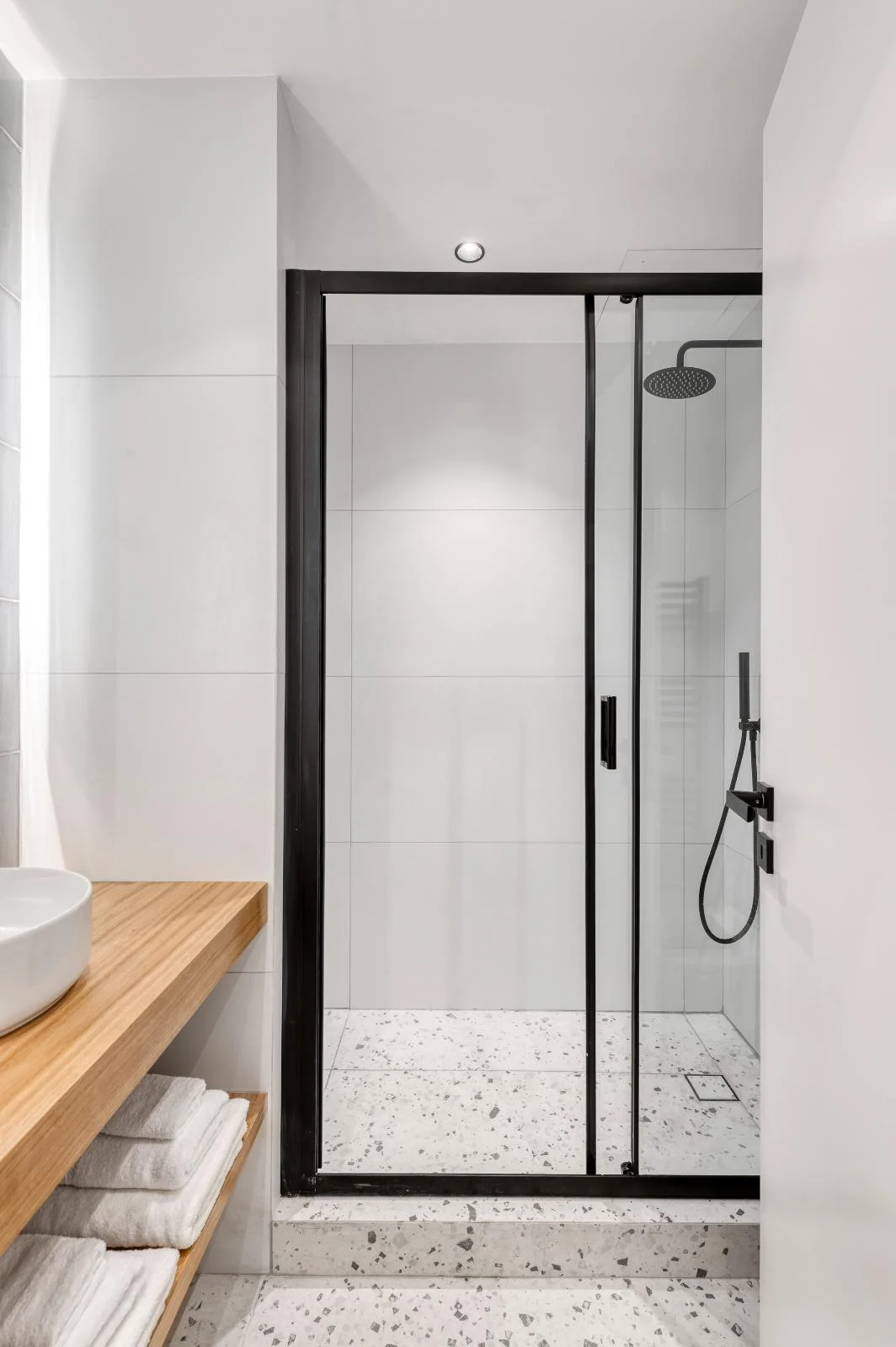Walk-in rainfall shower with black-framed glass at Dock 38
